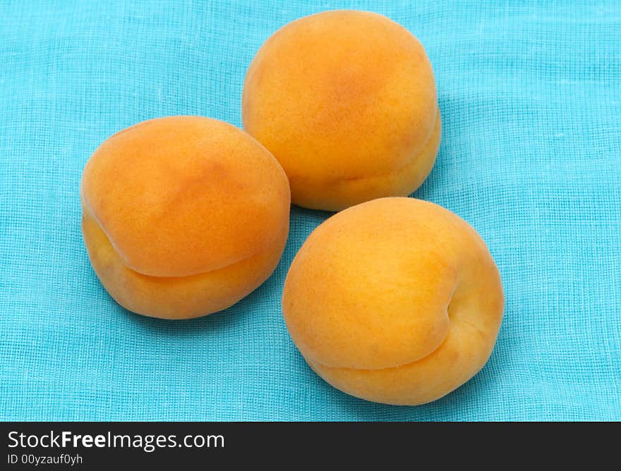 Three Apricots On A Blue Fabric