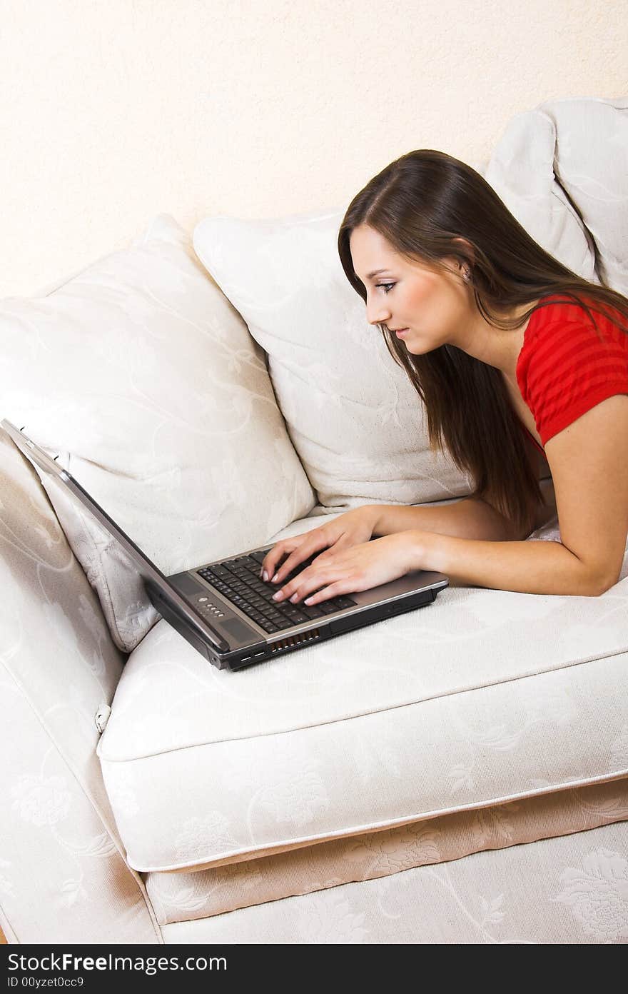 A young beautiful woman with a laptop on a lounge