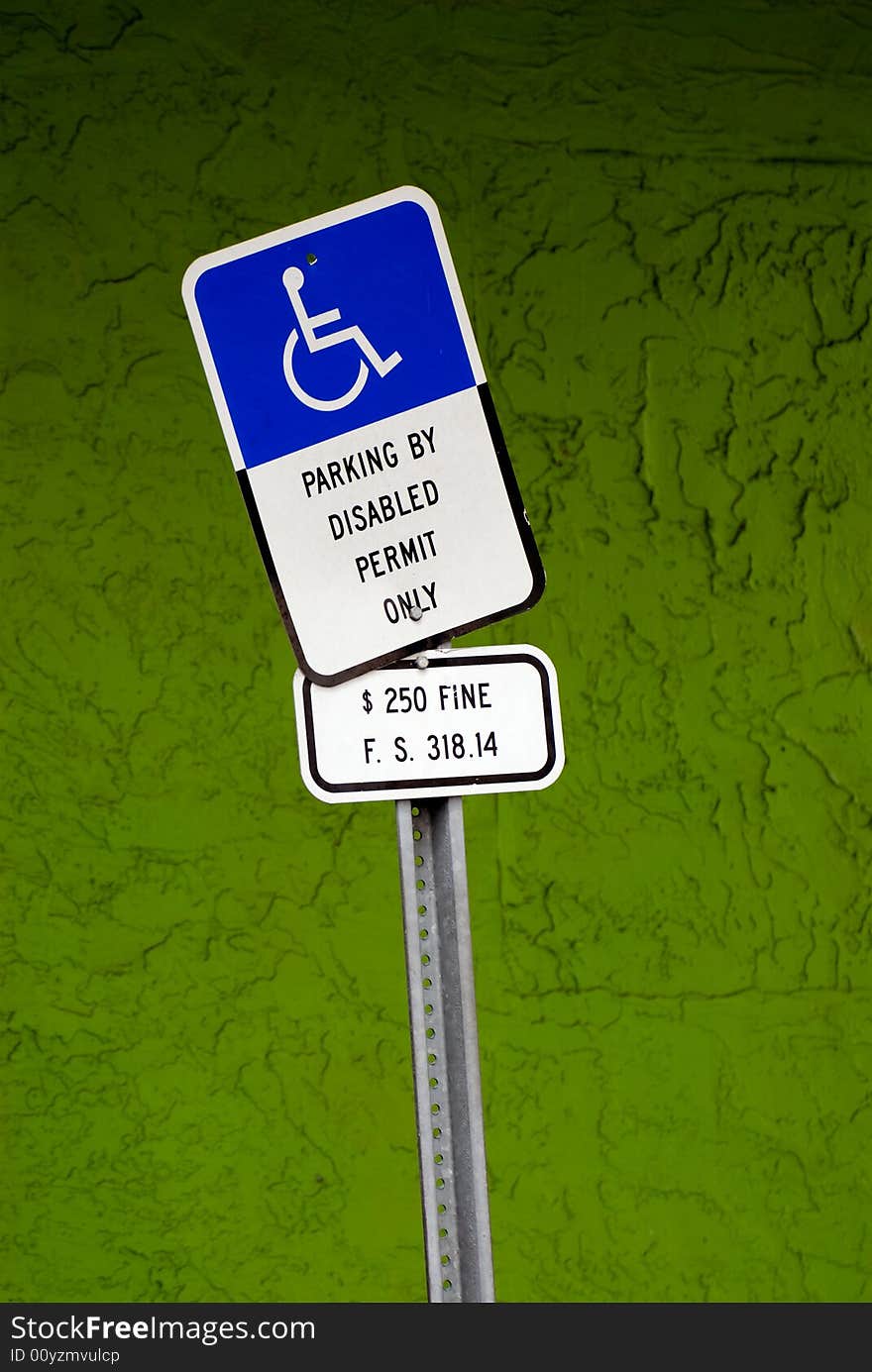 disabled parking sign in front of a green textured wall (sRGB). disabled parking sign in front of a green textured wall (sRGB)