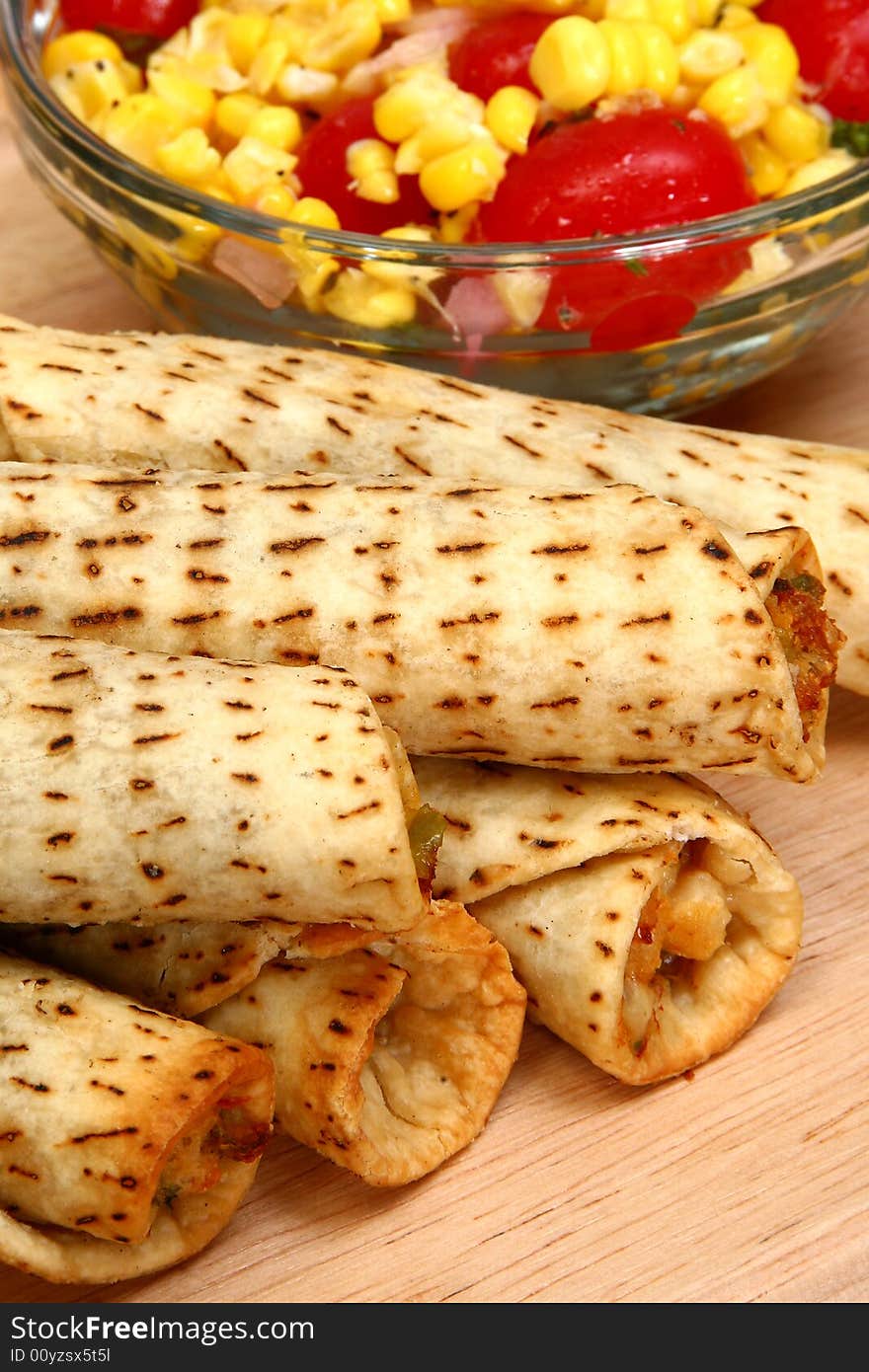 Stack of chicken taquitos with hot sauce and sour cream in kitchen or restaurant