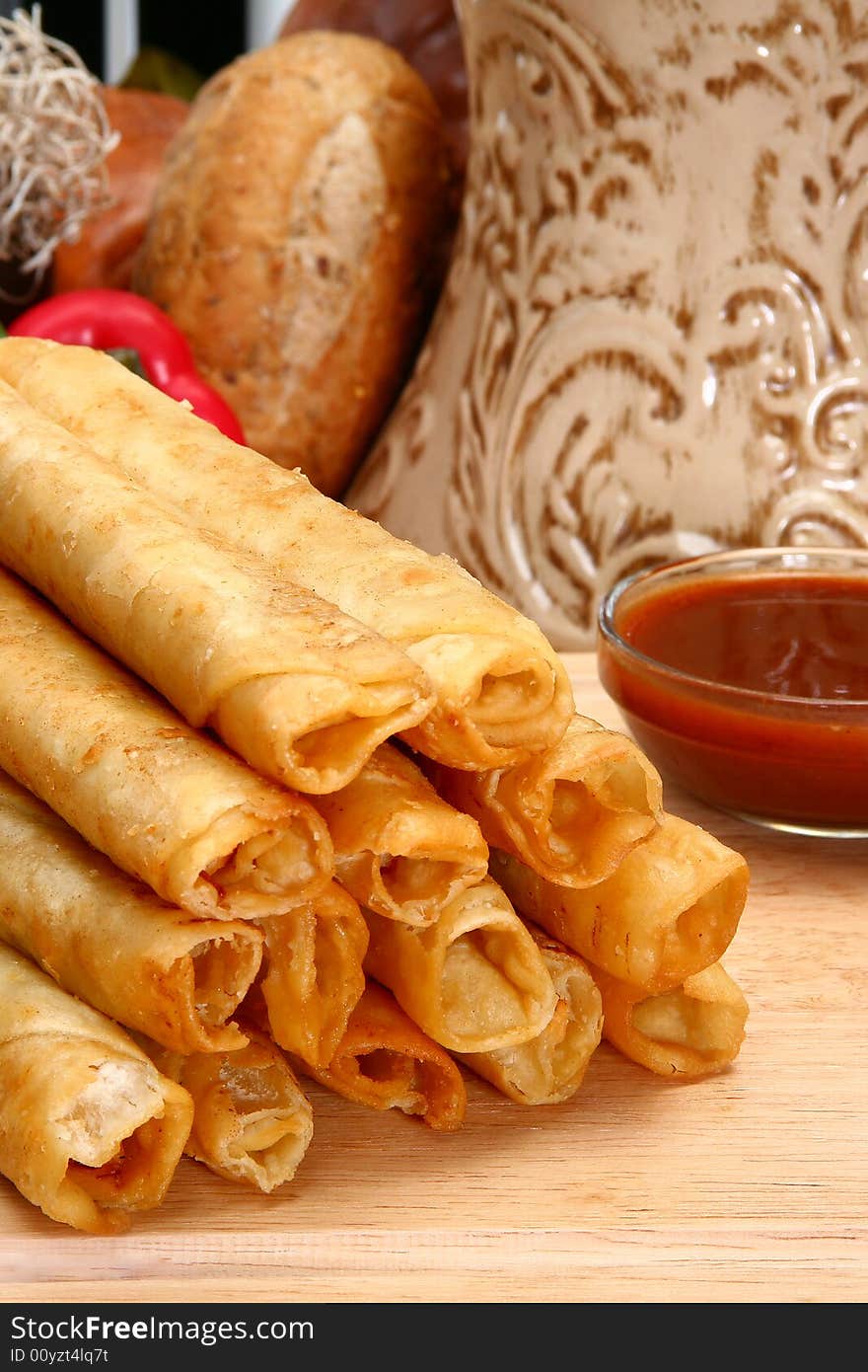 Stack of chicken taquitos with hot sauce and sour cream in kitchen or restaurant