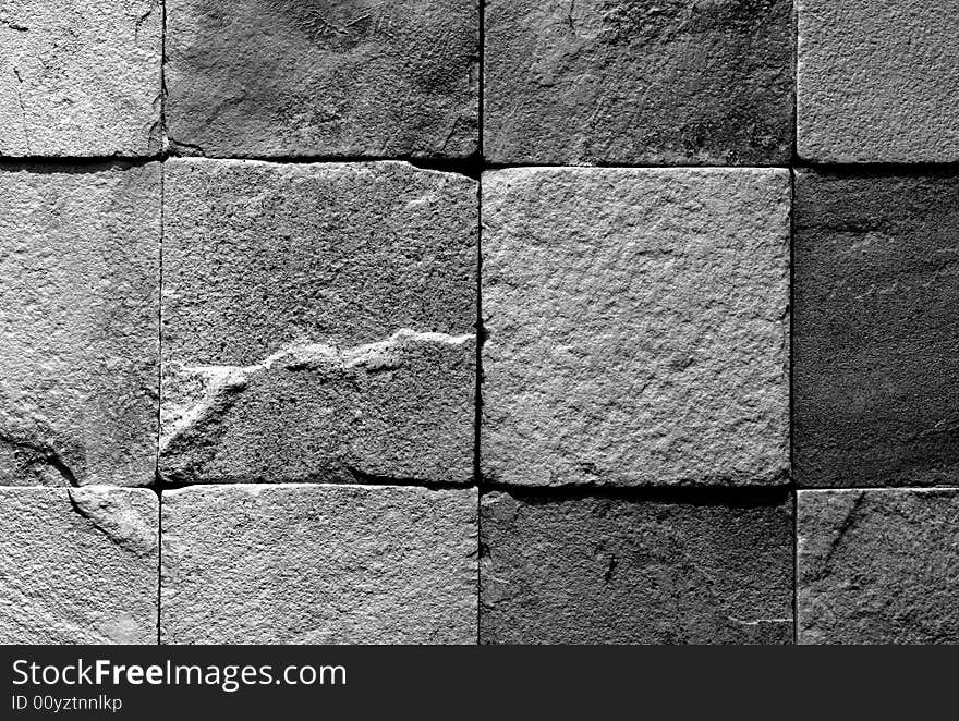 Black and white image of a section of wall made of roughly finished tiles. Black and white image of a section of wall made of roughly finished tiles