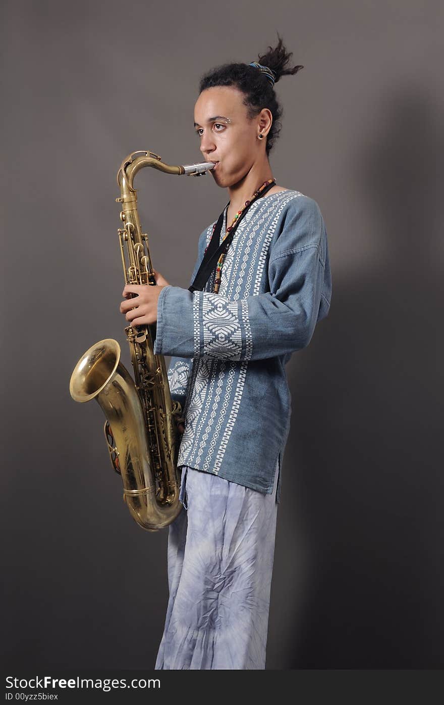 Portrait of young saxophone player in ethnic clothes