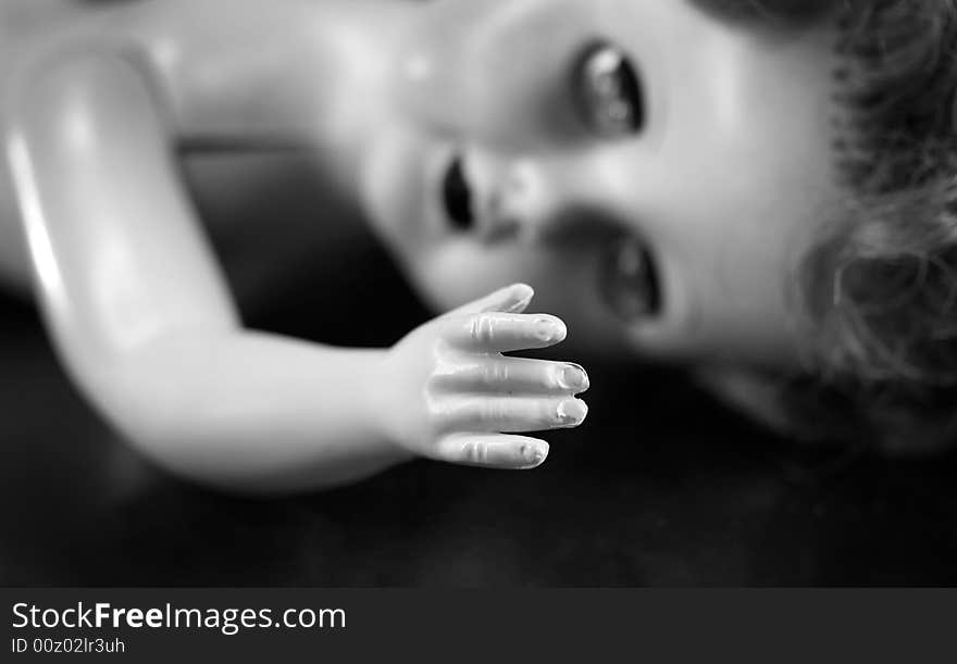 A black and white portrait of a broken doll with focus on the hand. A black and white portrait of a broken doll with focus on the hand