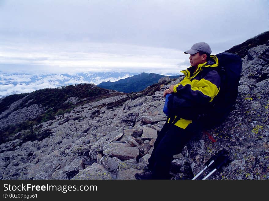 A hiker seating on the stone have a rest .Taibai mountain,About 4670m high.Shaanxi province,CHina. A hiker seating on the stone have a rest .Taibai mountain,About 4670m high.Shaanxi province,CHina.