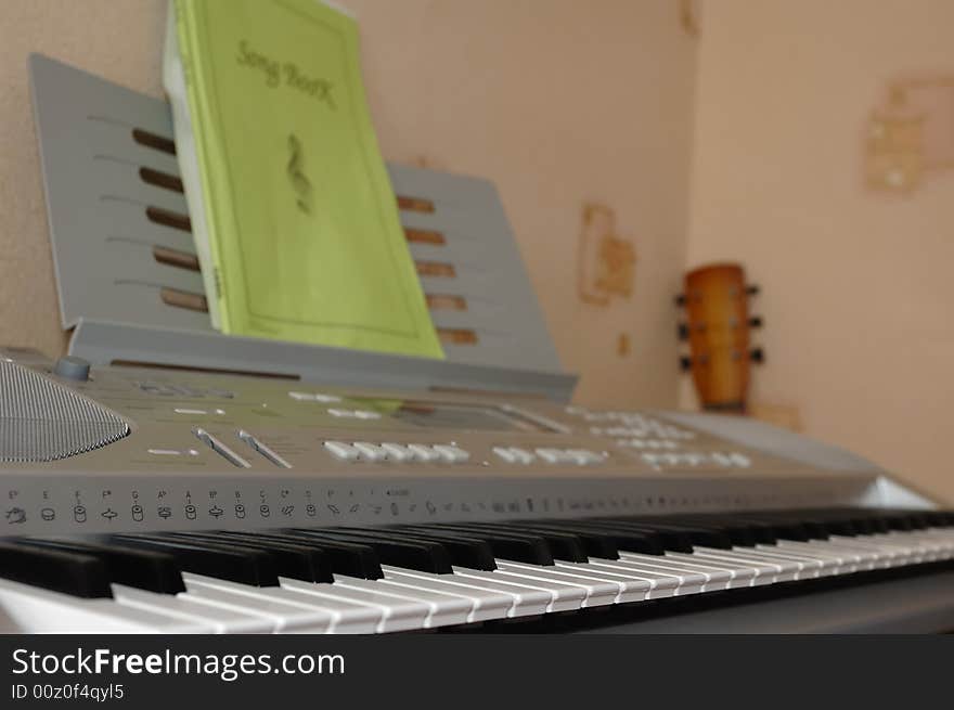 Photo of electric synthesizer and guitar neck in a room corner. Photo of electric synthesizer and guitar neck in a room corner