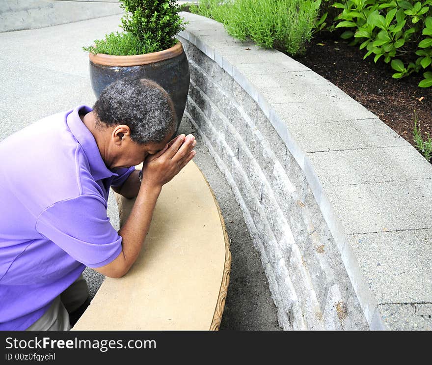 Muslim man praying outside on the ground.