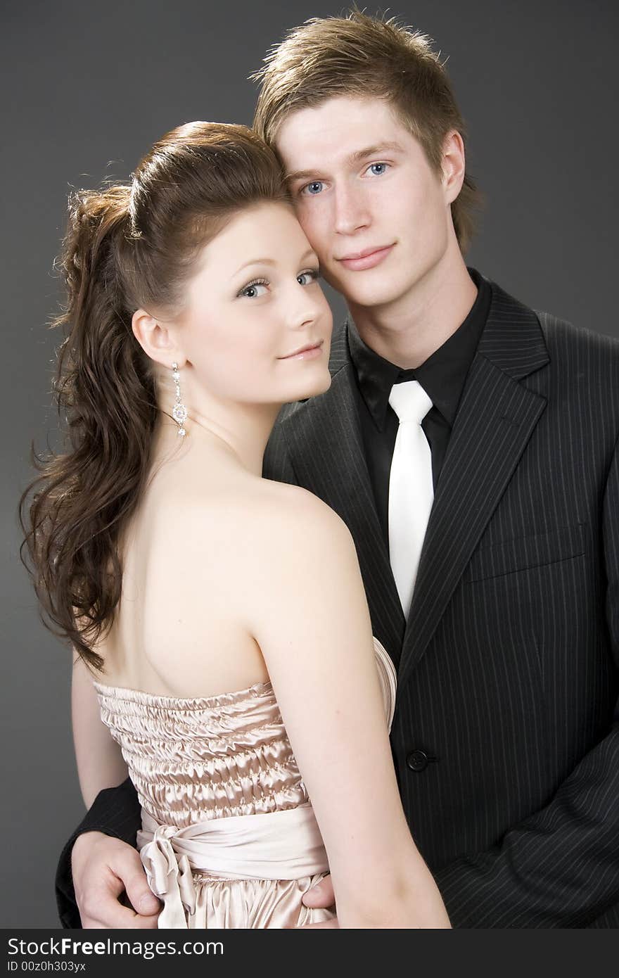 Portrait of a young beautiful couple embracing. (gray background)