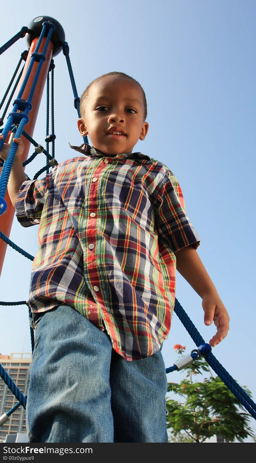 Young boy climbing to the top of a rope tower. Young boy climbing to the top of a rope tower.