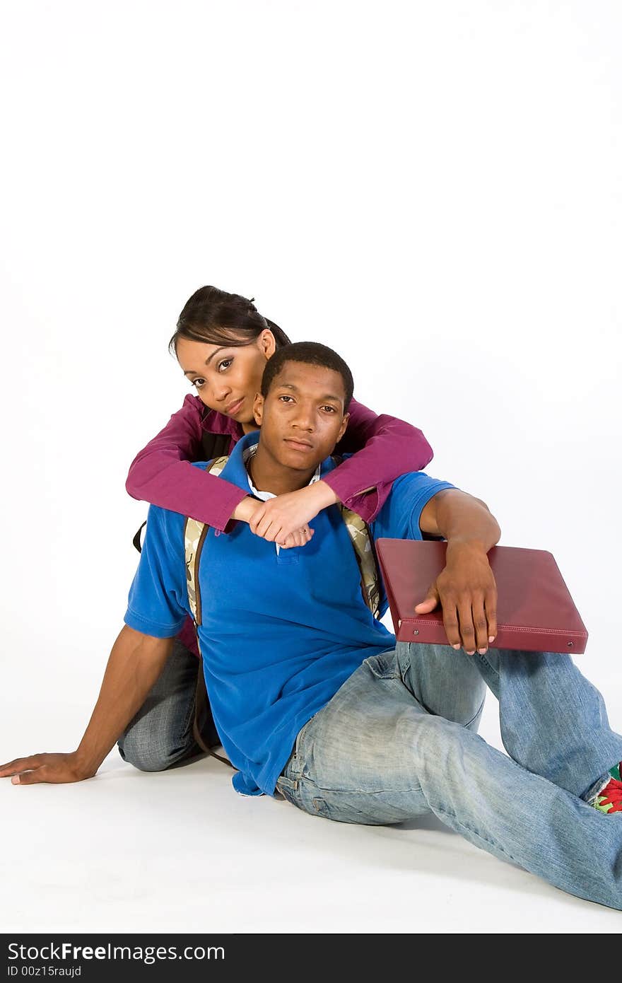 Two seated students look at the camera while she has her arms around his neck. Vertically framed photograph. Two seated students look at the camera while she has her arms around his neck. Vertically framed photograph