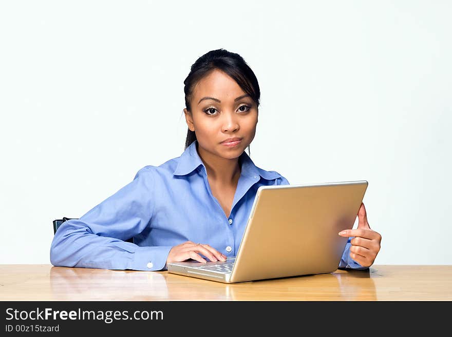 Female student working on her laptop appears bored while looking at the camera. Horizontally framed photograph. Female student working on her laptop appears bored while looking at the camera. Horizontally framed photograph