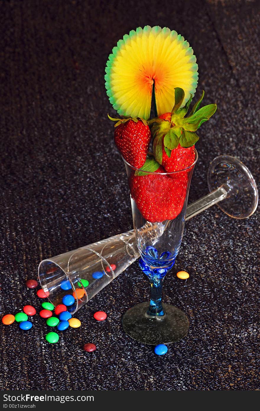 Composition made with Champagne glass full of strawberries and colorful chocolate drops. Composition made with Champagne glass full of strawberries and colorful chocolate drops