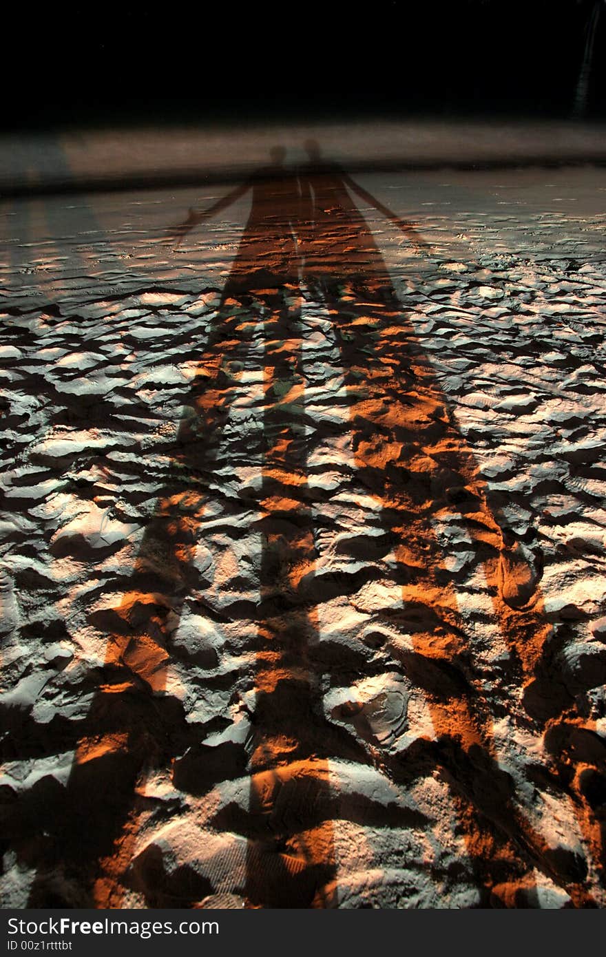 Long shadows of young couple at a beach