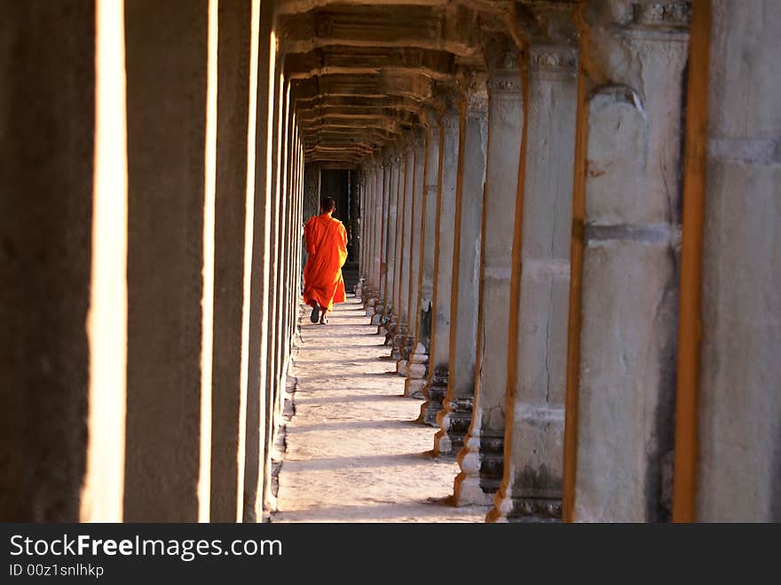 A monk walking through an ancient hall. A monk walking through an ancient hall.