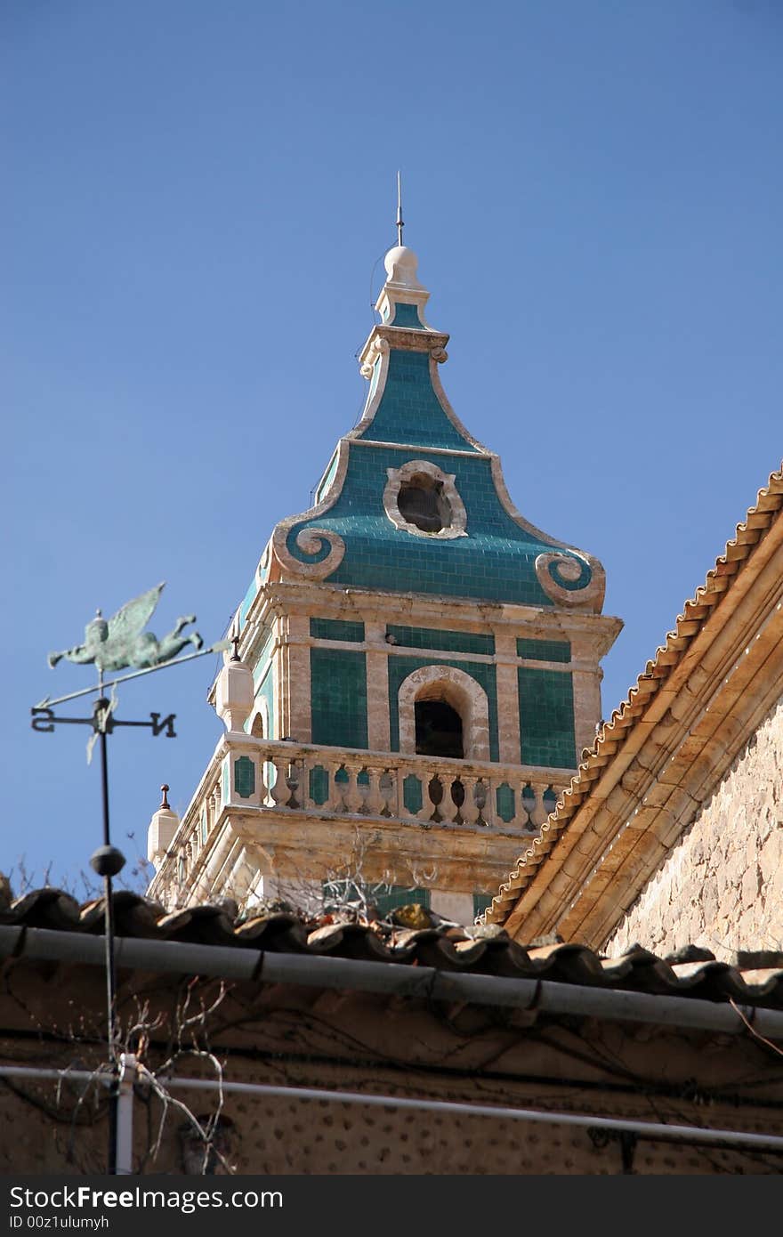 Church with coloured bell tower, with roofs infront