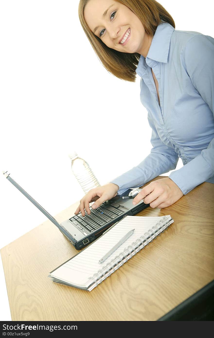 Young and pretty woman in casual dress using laptop but looking at camera and smile. Young and pretty woman in casual dress using laptop but looking at camera and smile