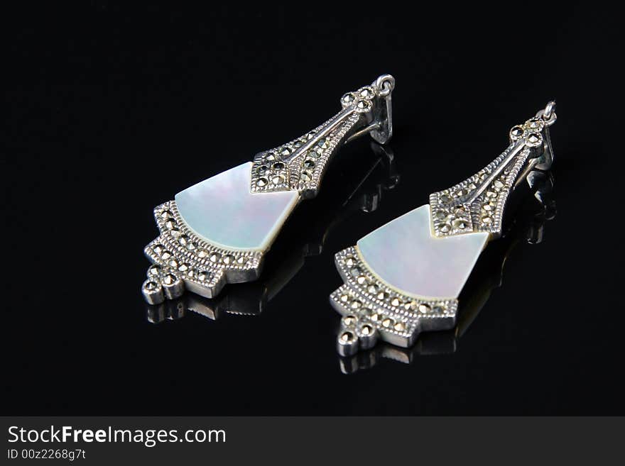 Earrings with mother of pearl and marcasita stones over black background