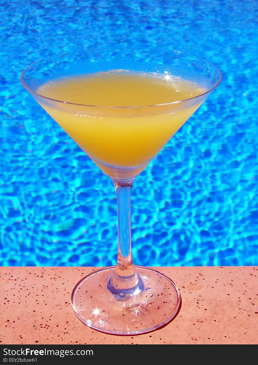 Glass of orange juice on pool edge. Glass of orange juice on pool edge