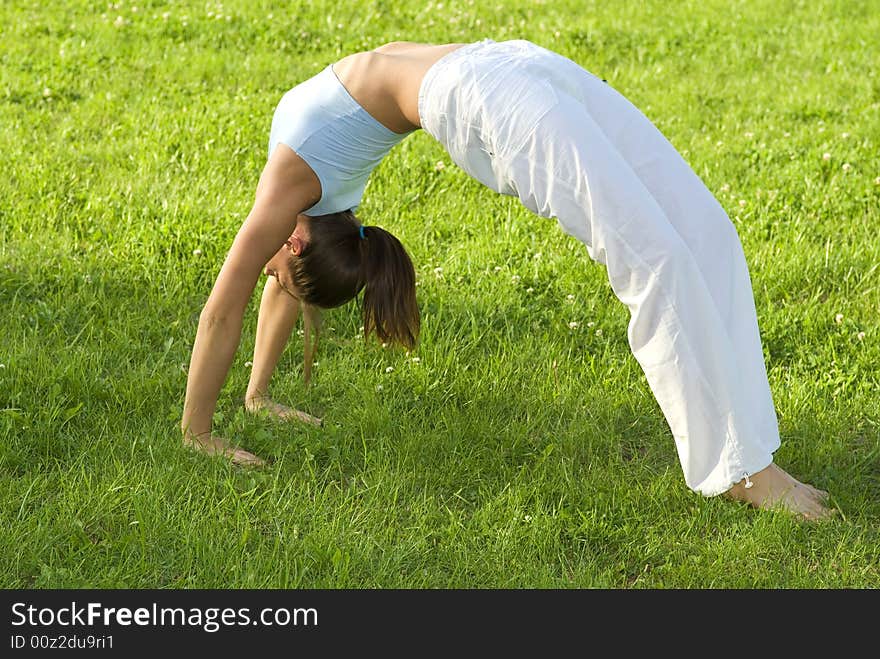 Sporty Girl Exercising On Meadow Against The Sky