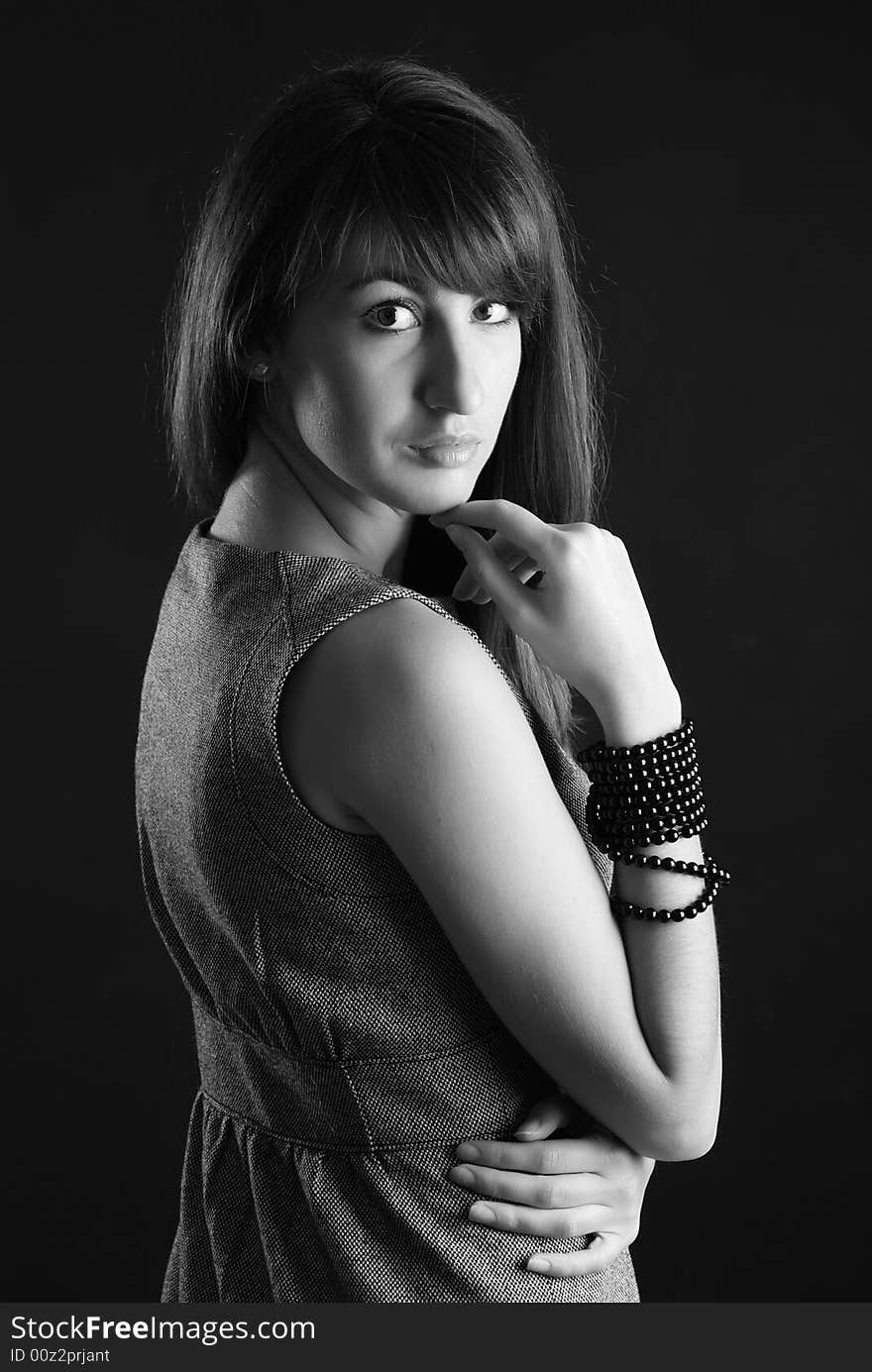 Young beautiful girl in grey clothes on a black background. Young beautiful girl in grey clothes on a black background