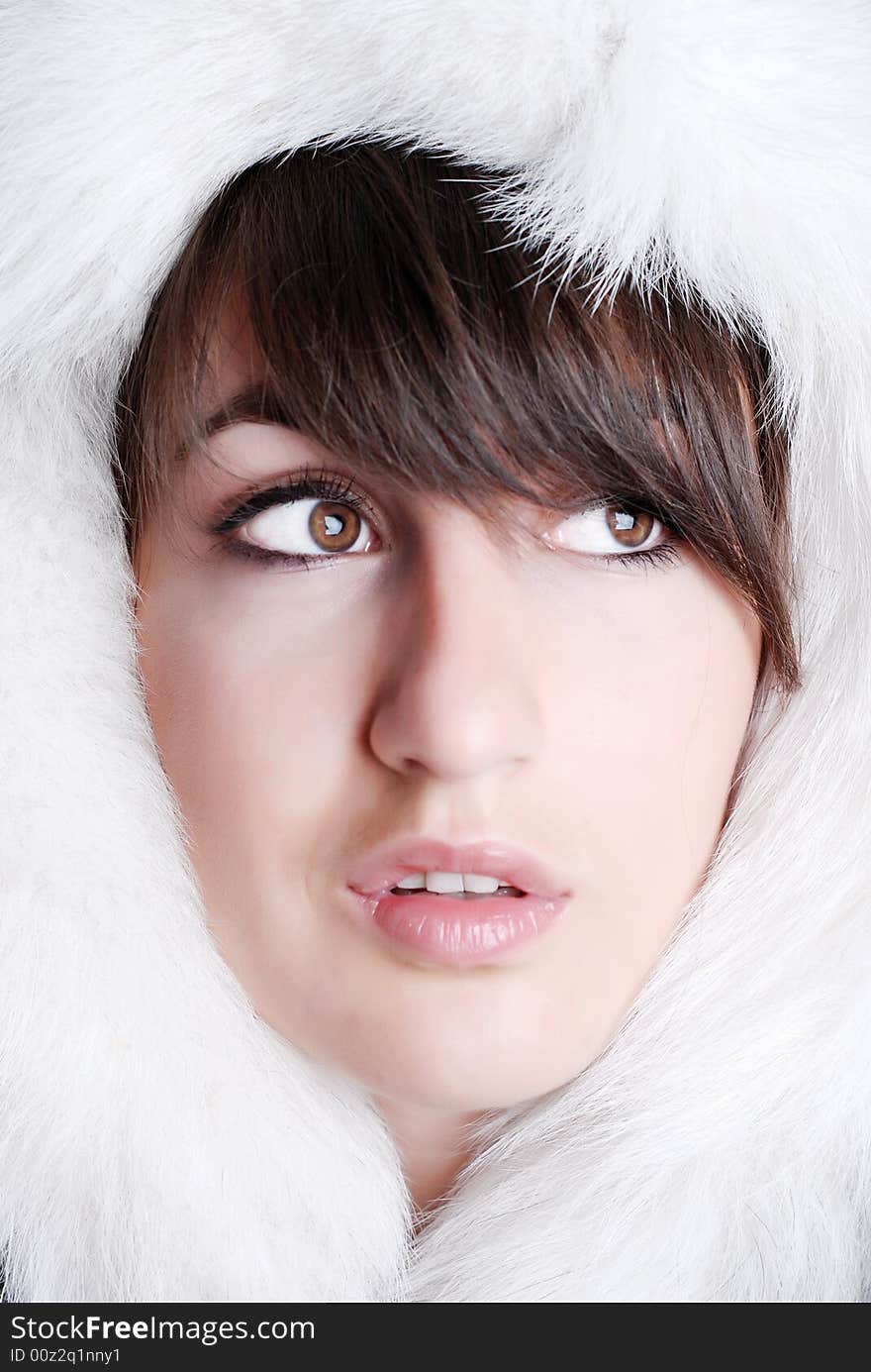 The face of young girl is surrounded white fluffy fur