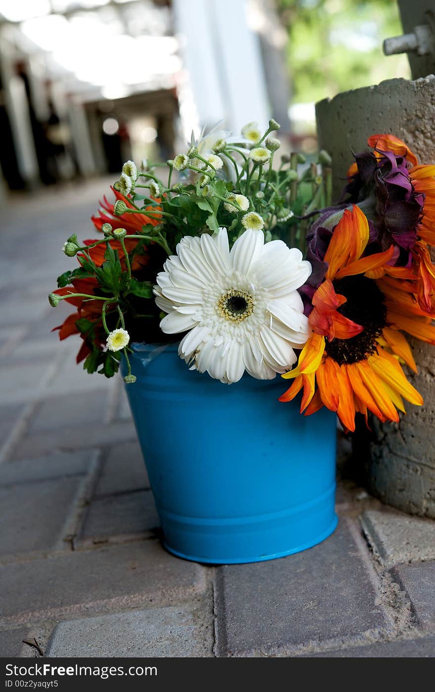 An image of a floral arrangement in a bright blue tin. An image of a floral arrangement in a bright blue tin