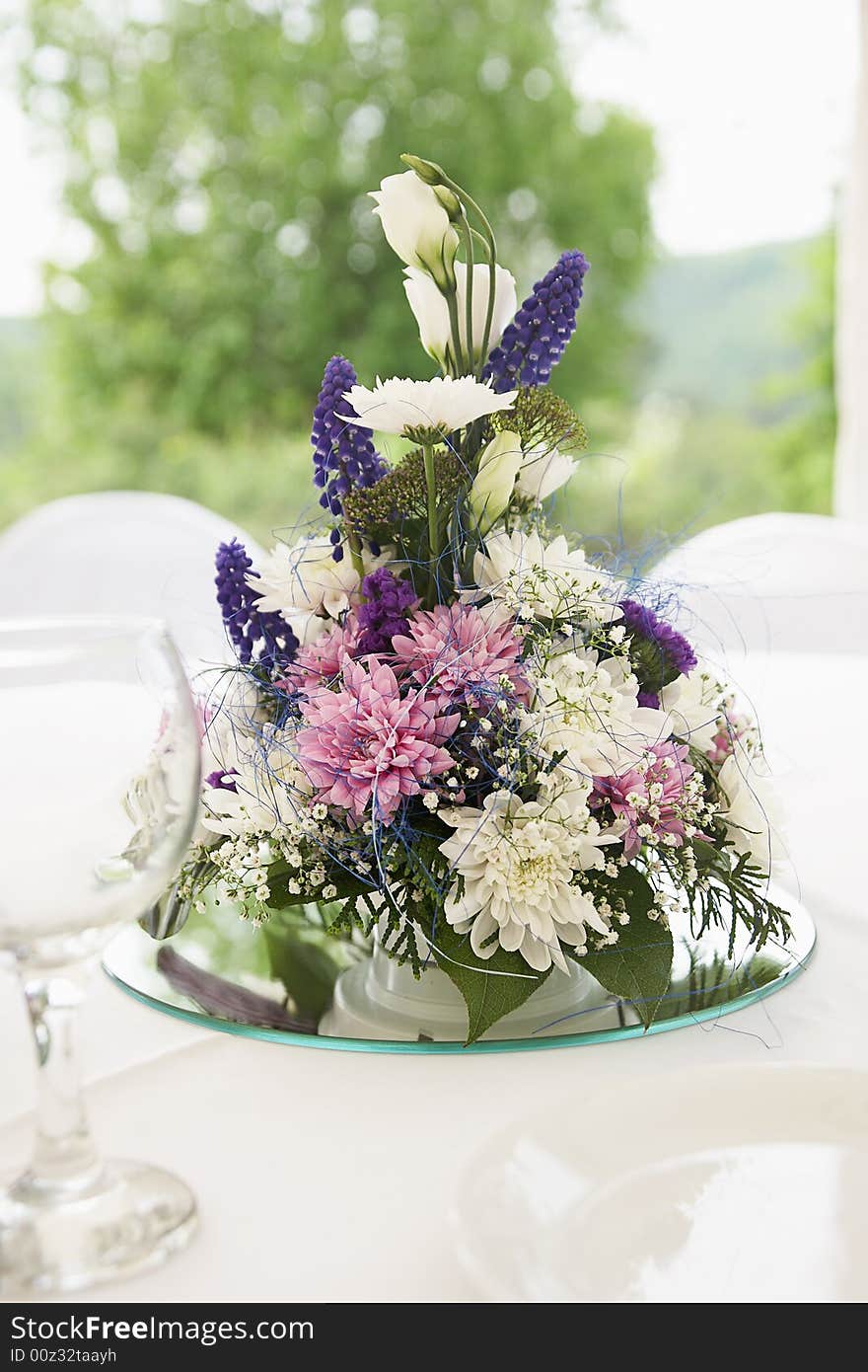 Flowers arranged in composition are standing on white dining table. Flowers arranged in composition are standing on white dining table