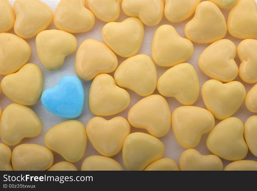 Heart shaped yellow with one blue candy candies background