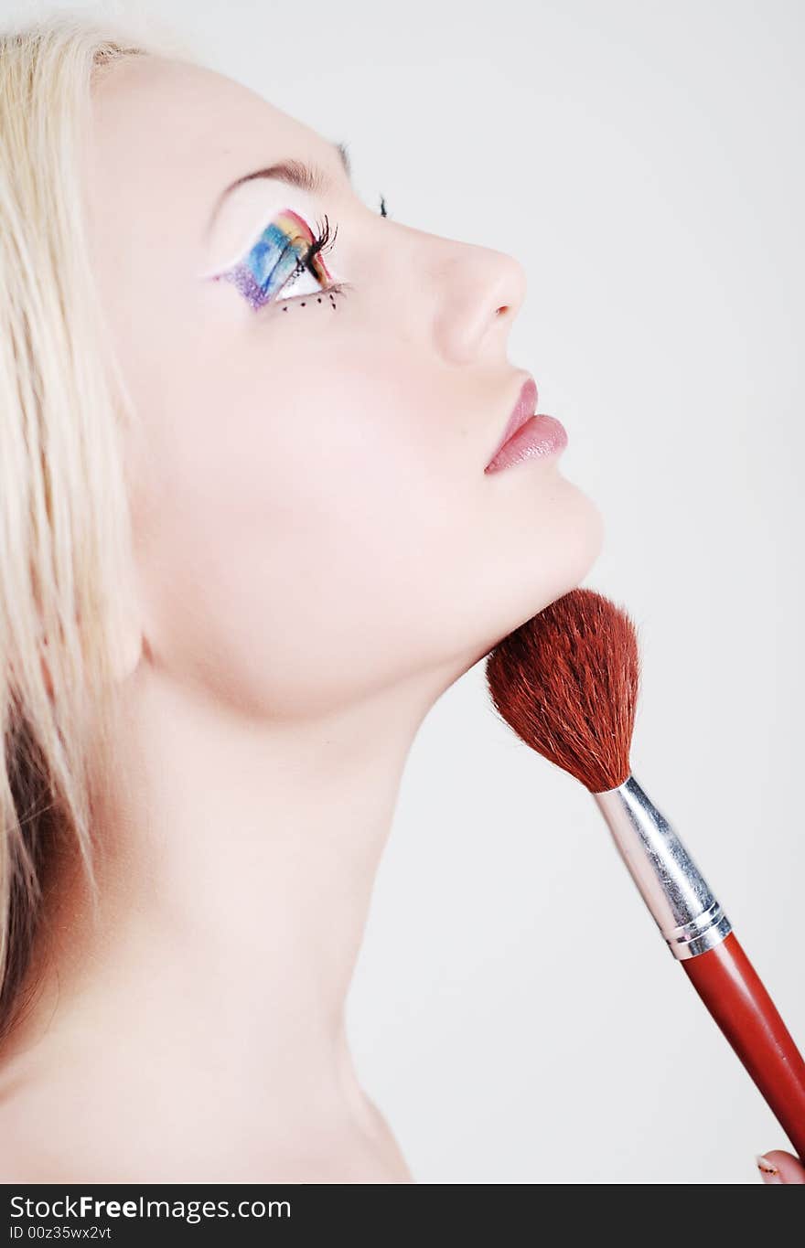 Beautiful girl with bright make-up, looks through a shoulder and holds a brush in a hand. Beautiful girl with bright make-up, looks through a shoulder and holds a brush in a hand