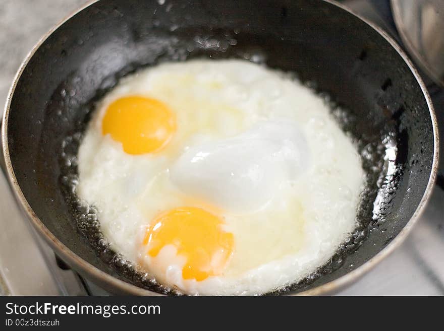 A pair of fried eggs over in a pan. A pair of fried eggs over in a pan.