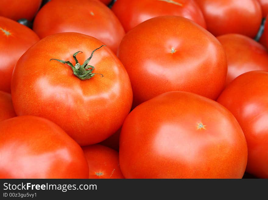 Fresh picked tomato with stem surrounded by other tomatoes. Fresh picked tomato with stem surrounded by other tomatoes
