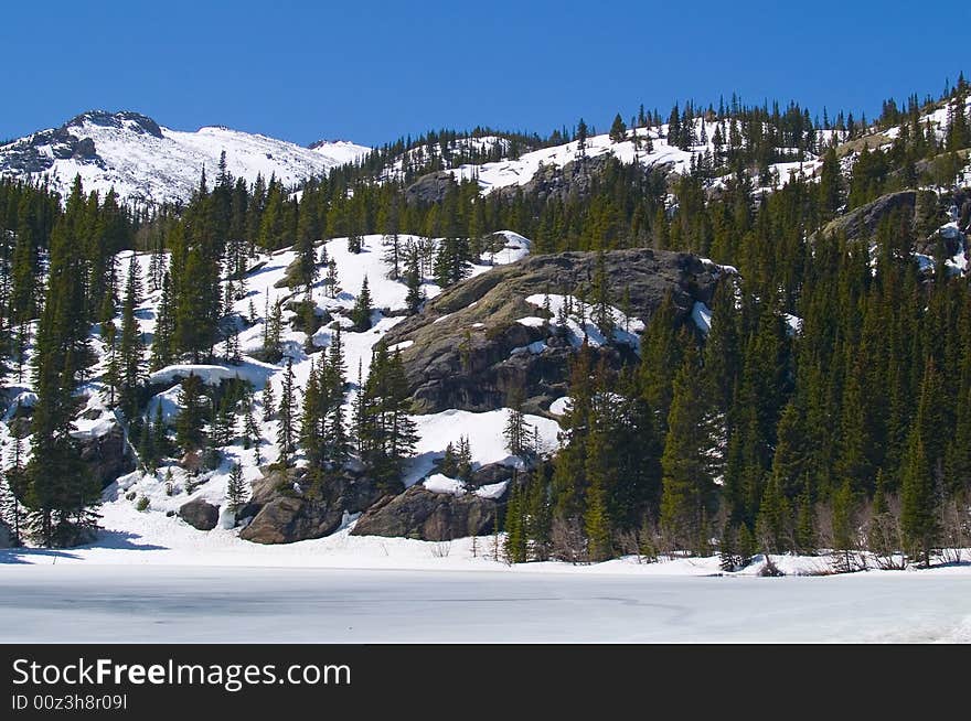 Christmas trees on a ridge above a frozen lake in Rocky Mountain National Park. Christmas trees on a ridge above a frozen lake in Rocky Mountain National Park