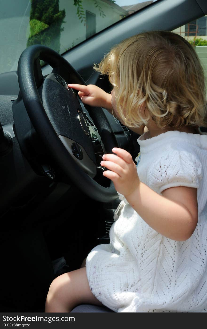 Little girl sits in a car and plays with the steering wheel, pretending to drive. Little girl sits in a car and plays with the steering wheel, pretending to drive.