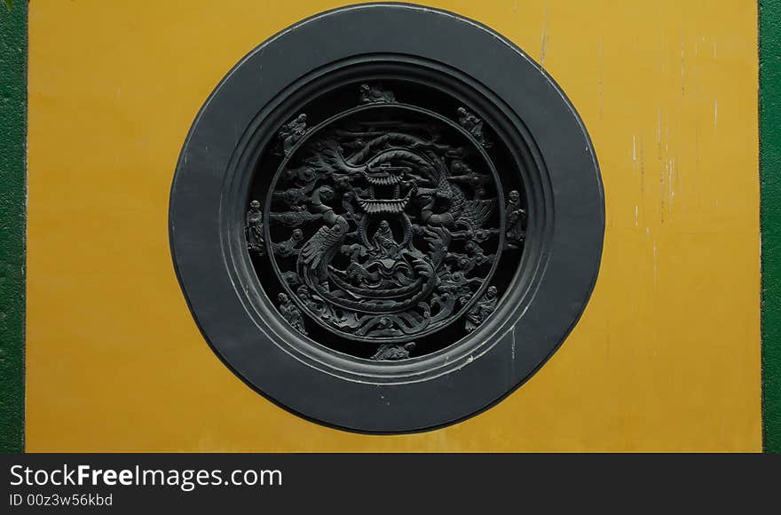 Round black window on the yellow wall in Lingyin Temple