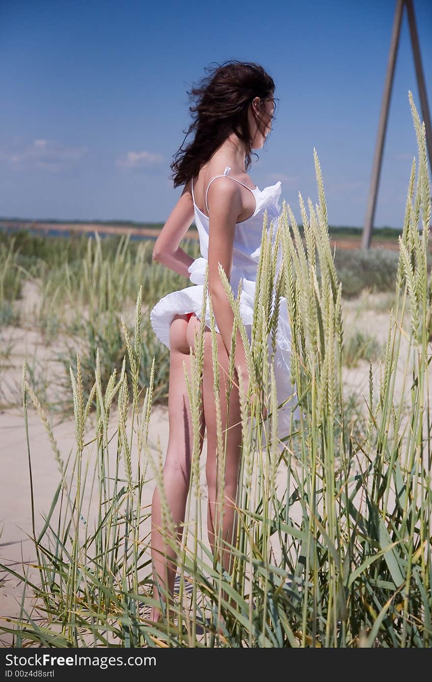 Beautiful girl in the grass on blue sky background