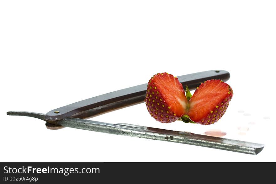 Strawberry and straight razor isolated on the white background