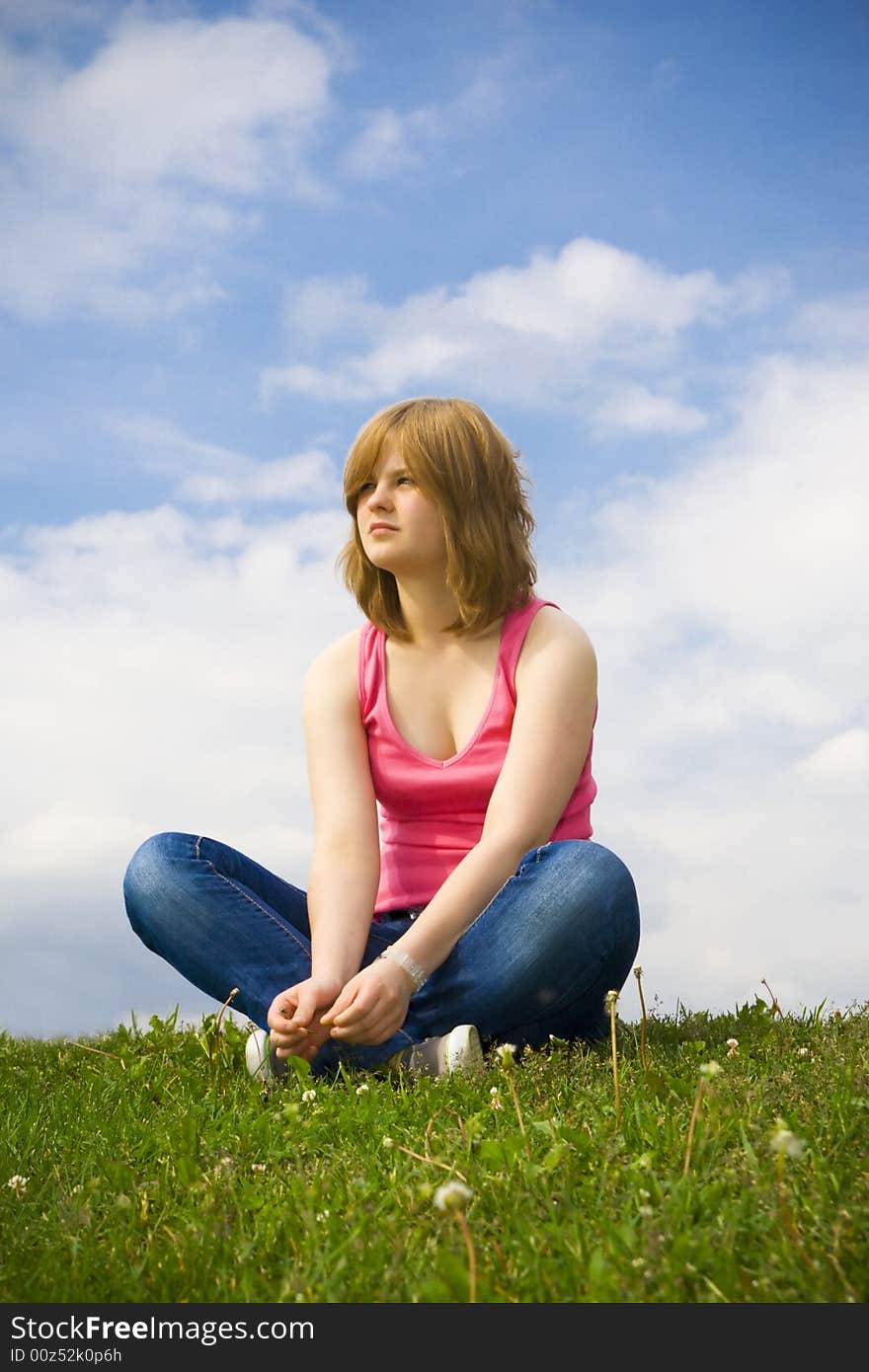 The young beautiful girl sitting on a green grass. The young beautiful girl sitting on a green grass