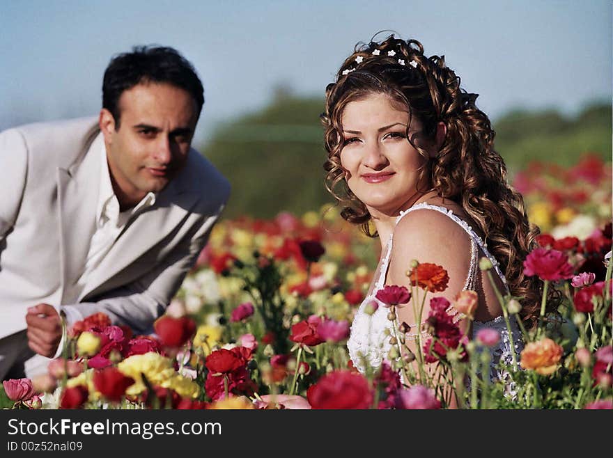 Groom and bride in the flower field holding flowers