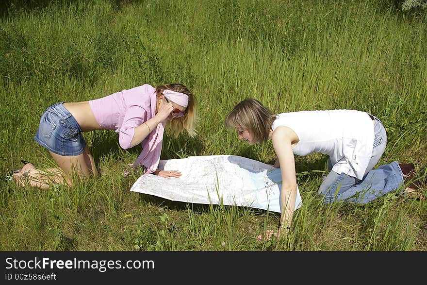 Two beautiful girls looks at the map on nature. Two beautiful girls looks at the map on nature