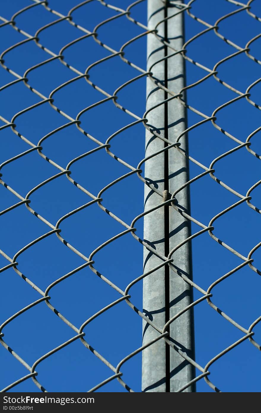 A chain link fence in front of a blue sky.