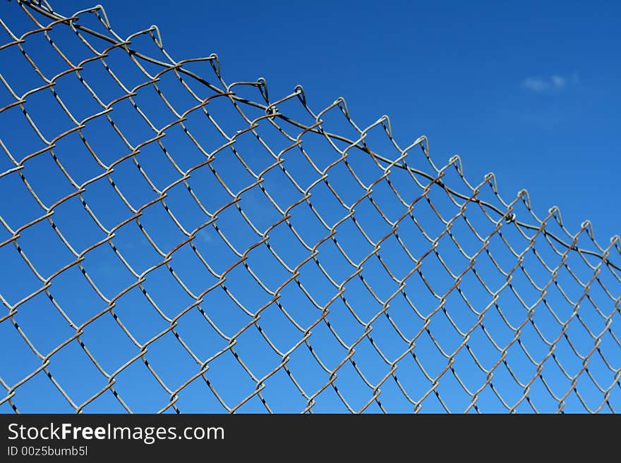 A chain link fence in front of a blue sky.