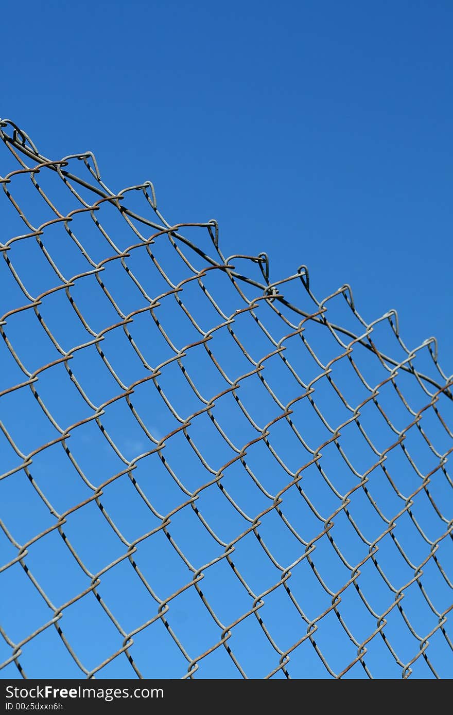 A chain link fence in front of a blue sky.