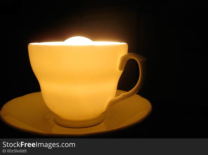 A cup with light in it, very close up angle view. dark background. A cup with light in it, very close up angle view. dark background.