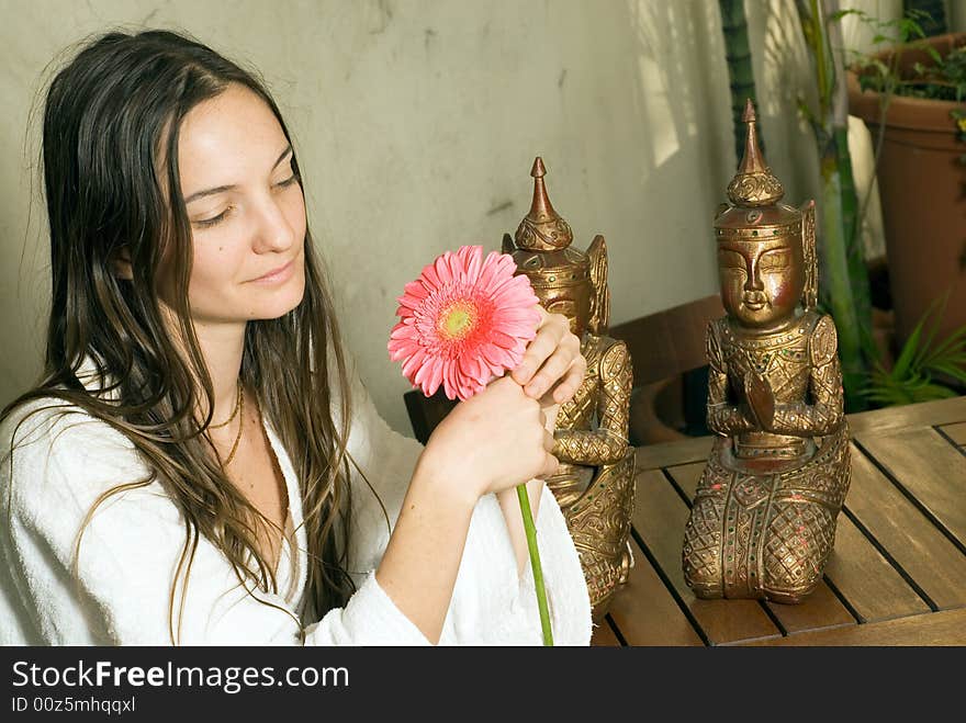 Woman Gazes at Pink Daisies. There are two bronze statues behind her. Horizontally framed photograph. Woman Gazes at Pink Daisies. There are two bronze statues behind her. Horizontally framed photograph