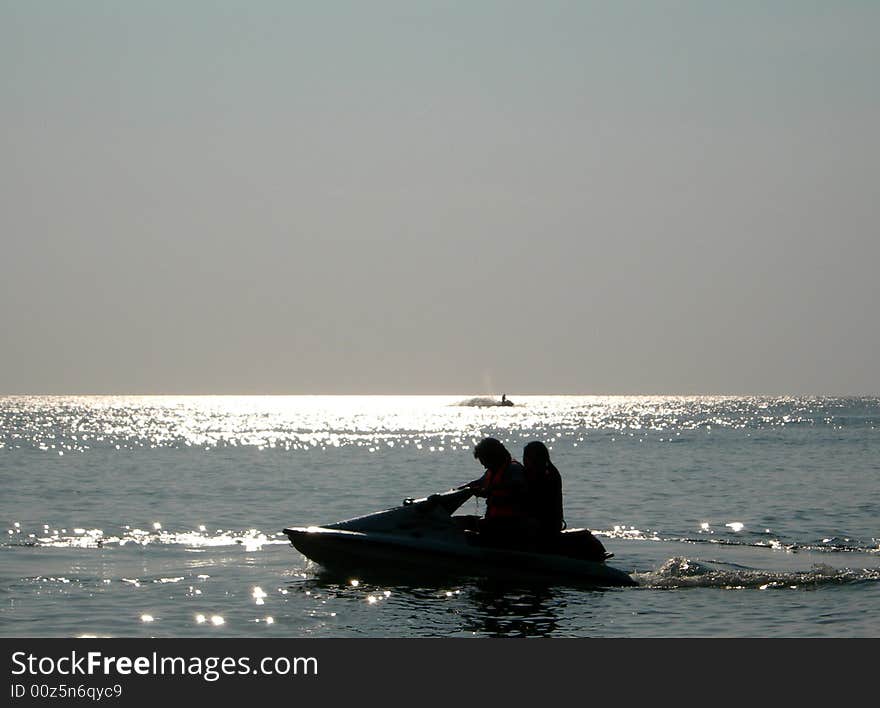 Couple haviing fun on waves with jet-ski under sunset. Couple haviing fun on waves with jet-ski under sunset