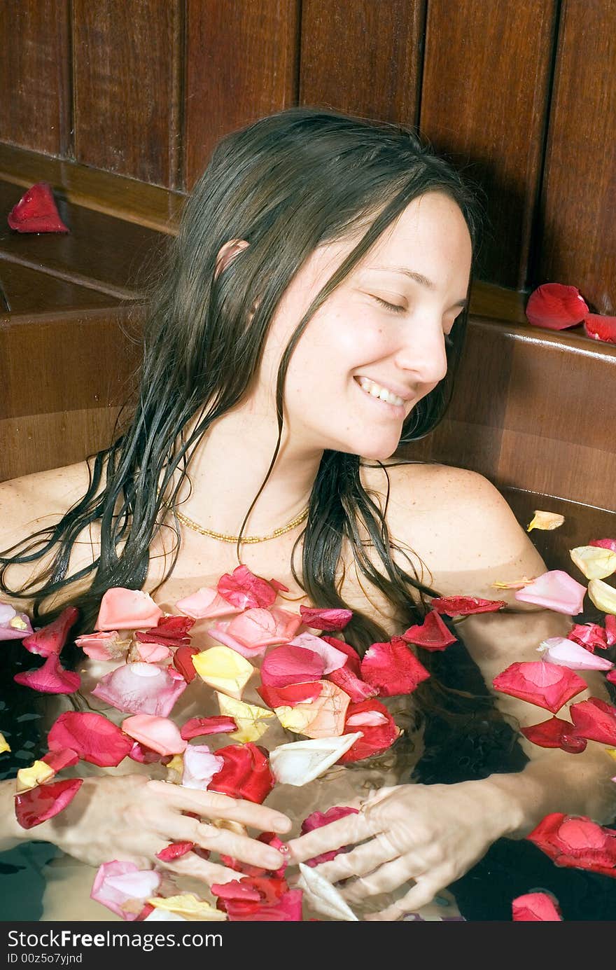 Woman relaxes in a spa tub filled with rose petals. She is closing her eyes and looks happy and relaxed. Woman relaxes in a spa tub filled with rose petals. She is closing her eyes and looks happy and relaxed.