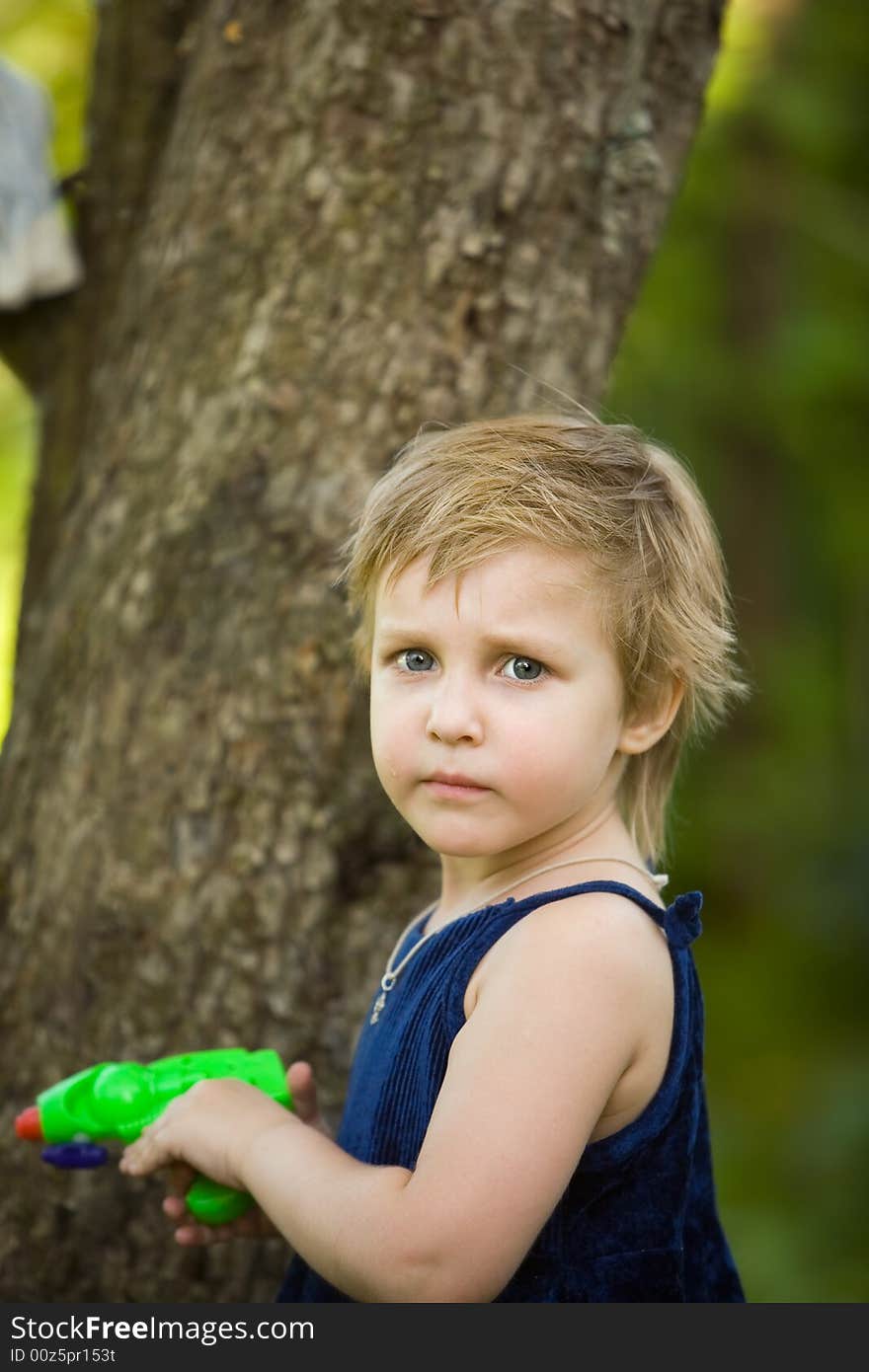 Little girl plays near a tree