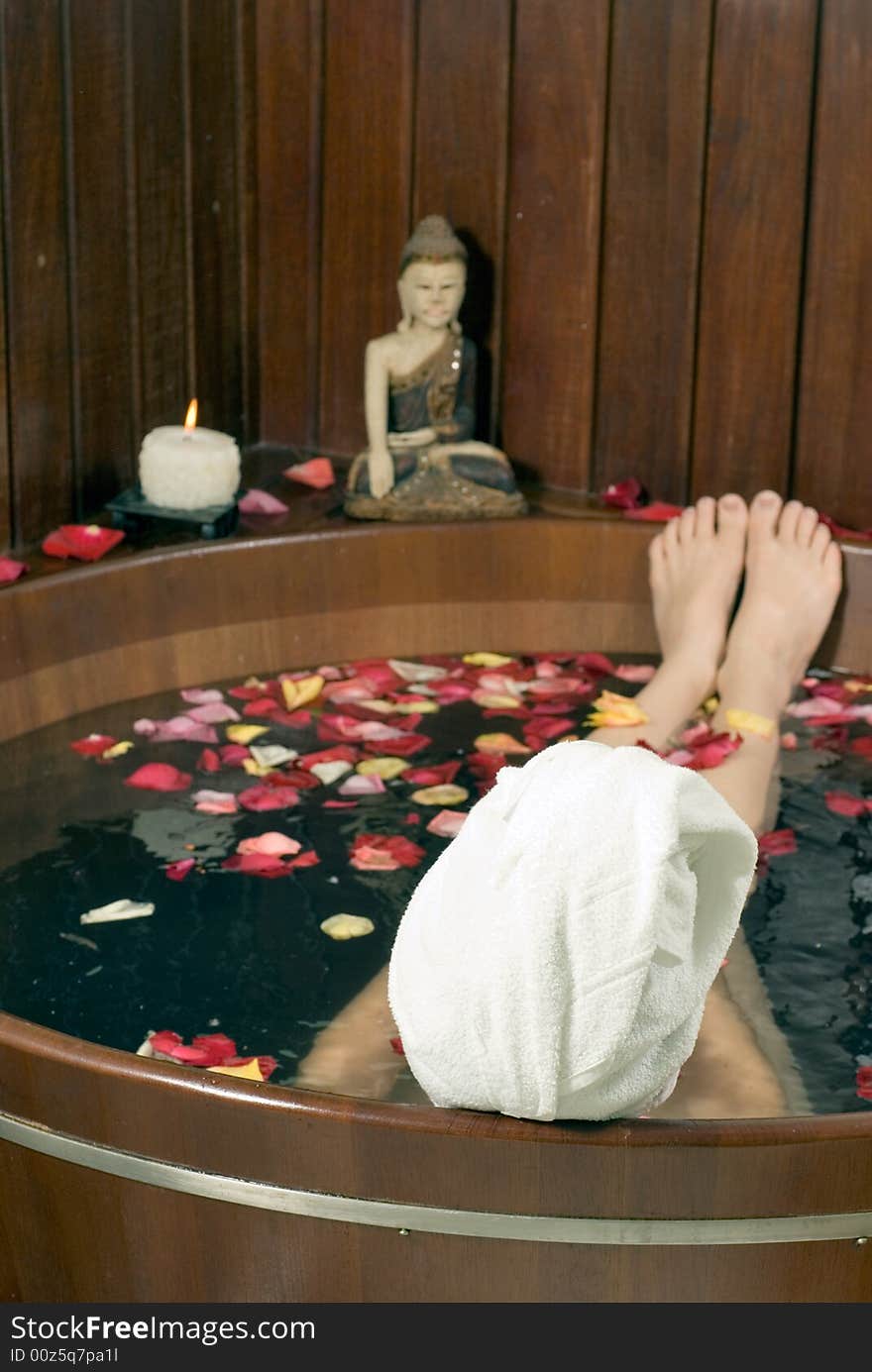 Picture of the back of a woman's head soaking in a tub filled with flower petals. Vertically framed photograph. Picture of the back of a woman's head soaking in a tub filled with flower petals. Vertically framed photograph