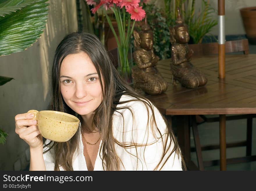 Woman smiles as she holds a tea cup. Horizontally framed photograph. Woman smiles as she holds a tea cup. Horizontally framed photograph.