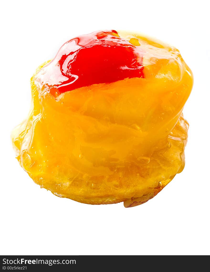 One small cake decorated with the a mango and a cherry close up on a white background. One small cake decorated with the a mango and a cherry close up on a white background